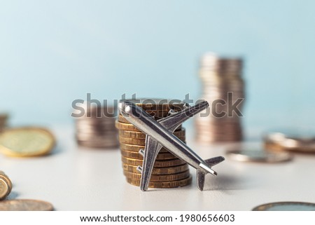 The airplane stands on a stack of coins. A toy little airplane is lying sideways on the gold coins. Royalty-Free Stock Photo #1980656603