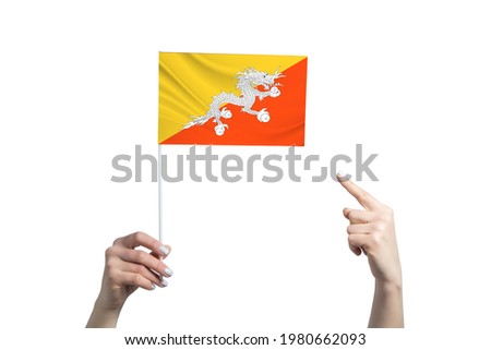 A beautiful female hand holds a Butane flag to which she shows the finger of her other hand, isolated on white background.