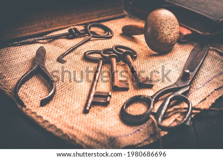 Old tools, books, keys and supplies on burlap in vintage style