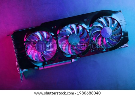 Gaming graphics card with neon magenta-cyan illumination and high-speed fans. Video chip for mining and powerful games in the cyberpunk concept.