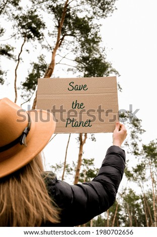 Female hands holding cardboard with text SAVE THE PLANET outdoors. Nature background. Protester activist. Social activism