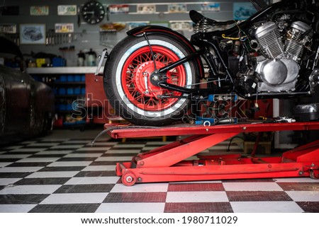 motorcycle raised on the platform to be repaired in a mechanic's shop. mechanics concept. vintage motorcycle Royalty-Free Stock Photo #1980711029