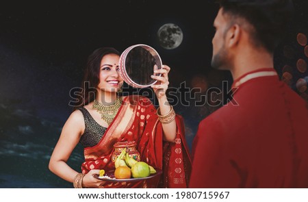 Indian woman celebrating Karva Chauth by looking at her husband after looking at the moon at night Royalty-Free Stock Photo #1980715967