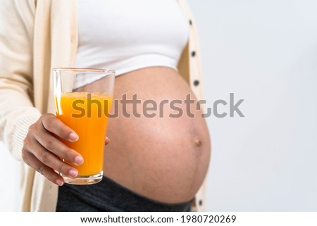 A 28 week pregnant woman holds an orange juice and chooses a nutritious diet for the healthy development and growth of her unborn child.