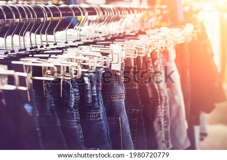 Many hangers with jeans hang on the counter in the store. Tinted photograph. Soft focus.