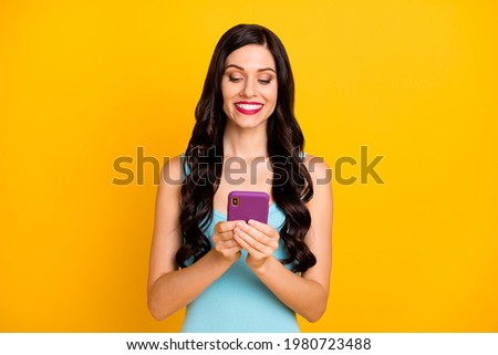 Photo of pretty young girl hold telephone look screen wear blue top isolated yellow color background