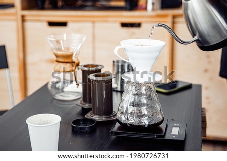 Alternative method of making coffee, funnel drip glasses with paper filter pour over kettle process. Royalty-Free Stock Photo #1980726731