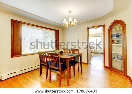 Ivory dining room with wooden dining table set, shiny hardwood floor and built-in cabinet with glass door