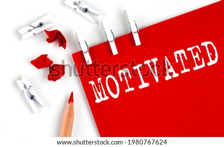 MOTIVATED text on red paper with office tools on the white background