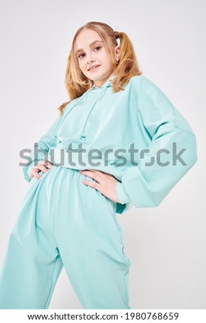 Youth style. Carefree cute teenage girl in trendy mint hoodie and sweatpants poses on a white background. Positive emotions. 