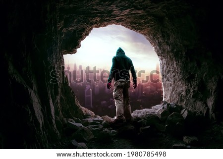 Man inside the cave looking at the city
