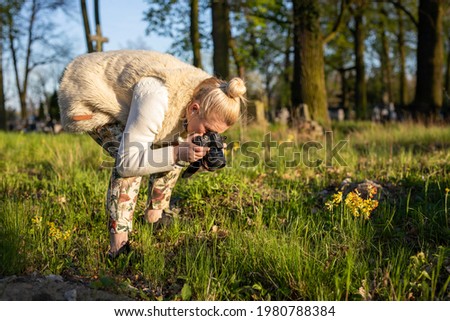 young woman photographs flowers in the meadow, photographing nature