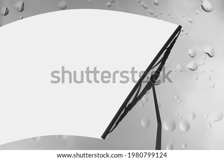 Car windshield wiper cleaning water drops from glass Royalty-Free Stock Photo #1980799124