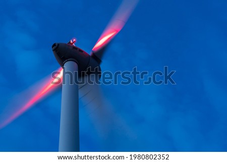 Close-up with the movement of the propeller of a wind turbine producing renewable green energy during night. Copy space, motion blur. Royalty-Free Stock Photo #1980802352