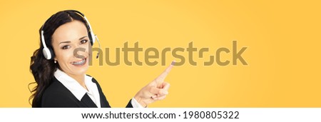 Call center service. Portrait of customer support phone sales operator in headset showing advertising something or copy space area for text, imaginary, product or slogan, over orange yellow background