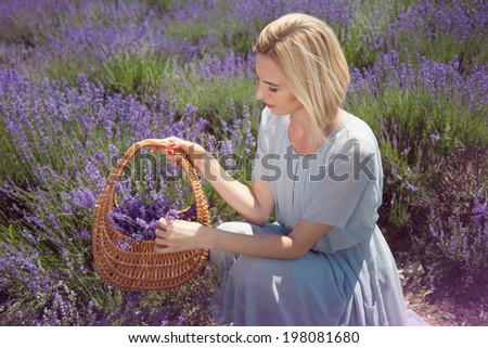 Young beautiful woman with a wicker basket in a lavender field