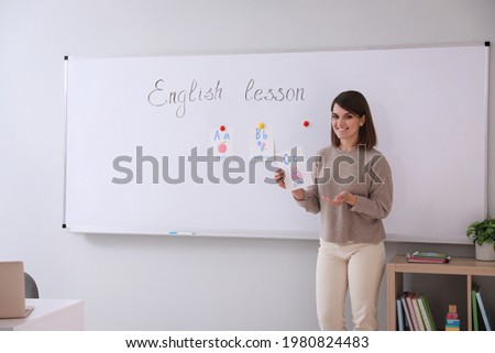Happy female English teacher giving lesson indoors. Early childhood education