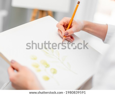 Woman hands holding white canvas paper and graphic pencil and drawing sketch