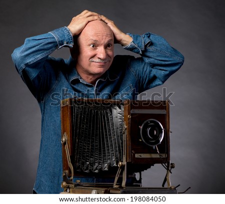 Man with vintage wooden photo camera on a dark background