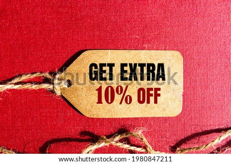 GET EXTRA 10 OFF percent text on a brown tag on a red paper background