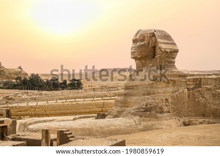 Landscape with Egyptian pyramids, Great Sphinx and silhouettes Ancient symbols and landmarks of Egypt for your travel concept to Africa in golden sunlight. Sphinx head against the yellow sky