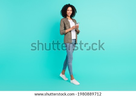 Full length body size view of attractive cheerful thin girl using gadget comment media isolated over bright blue color background