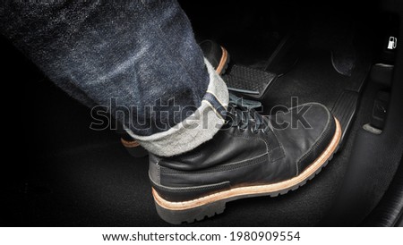 Foot pressing foot pedal of a car to drive. Accelerator and brake pedal in a car. Driver driving the car by pushing accelerator and break pedals of the car. inside vehicle. control pedal. Close up. Royalty-Free Stock Photo #1980909554