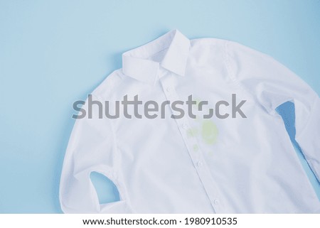 Drops of cocktail spilled on a white shirt. Cleaning concept. isolated on blue background. top view. High quality photo Royalty-Free Stock Photo #1980910535