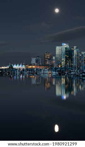 Picture of downtown vancouver canada on a clear night with a full moon, taken from Stanley park