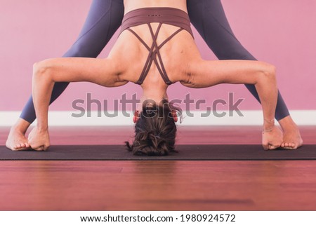 Middle-aged white woman practices yoga on pink background. Relaxed