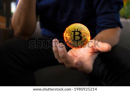 burning golden bitcoin in a businessman hand in the office with soft focus and backlighting. cryptocurrency concept