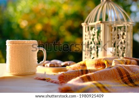 tea, coffee in a mug on the table in the garden, a candle is burning in a candlestick, the concept of outdoor tea drinking, good weather, a cozy autumn mood