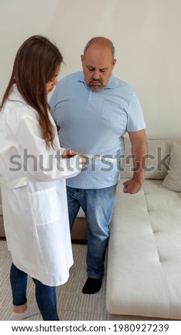Overweight man with young female doctor in white coat standing in the medical room. Young woman doctor with tailors centimeter measuring overweight man. Unhealthy Lifestyle Concept.