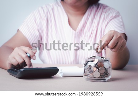 Save money concept, business woman hand holding coins into glass jar use calculator, saving money growth for future finance accounting conceptual, banking and saving business idea concept.