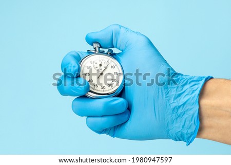 Doctor in glove holds stopwatch in his hand. Fast medical assistance and consultation concept. Royalty-Free Stock Photo #1980947597