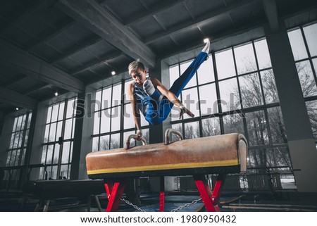 Leader. Little male gymnast training in gym, composed and active. Caucasian fit boy, athlete in sportswear practicing in exercises for strength, balance. Movement, action, motion, dynamic concept