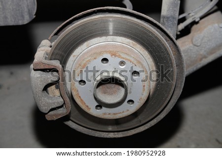 Car brakes system wheel part closeup - used unvented brake disk with brake caliper with brake pads