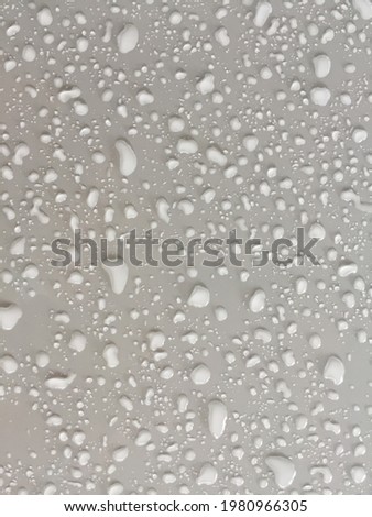 Drops of water on a matte gray car hood,Water droplets on the matt gray bonnet, and a white object surface.