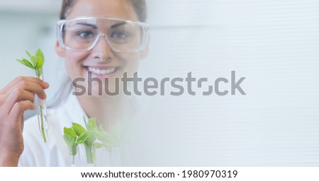 Composition of caucasian female scientist holding plant in test tube with copy space. science, botanics and research concept digitally generated image.