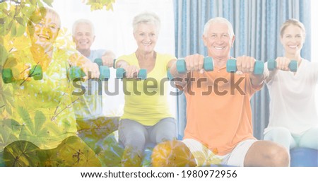 Composition of senior men and women lifting dumbbells in fitness class with tree overlay. retirement, fitness and active lifestyle concept digitally generated image.