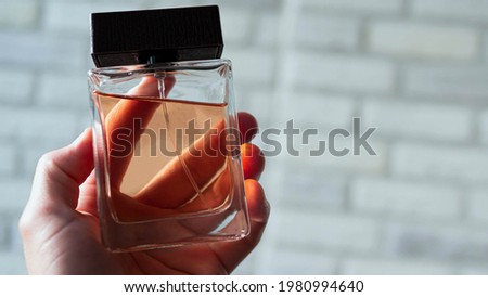 Man's perfume in a man's hand. Jar for spirits copy space.