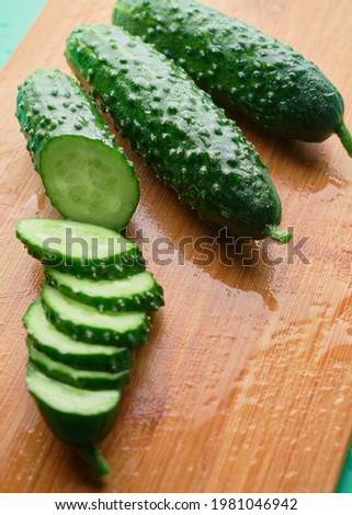 Set of fresh whole and sliced cucumbers on a wooden board with water drops. Garden cucumber wallpaper backdrop design