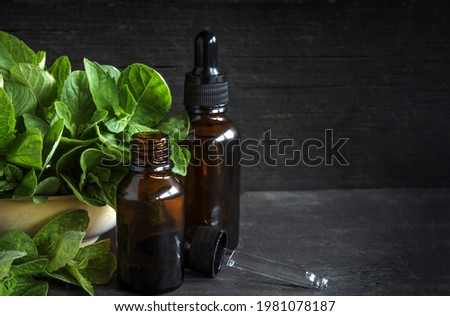 cosmetic oils of mint on a black wood background with a copy of the space.