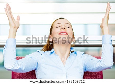 Closeup portrait happy young business woman in blue shirt looking upwards, hands raised in air relaxing on red couch, armchair isolated city background. Corporate life style. Stress relief techniques Royalty-Free Stock Photo #198109712