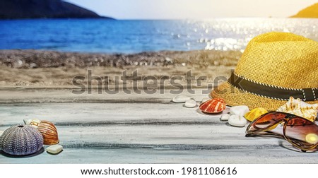 Summer holidays, angle view background concept with copy space for product pack shots. Panama hat, shells beach shingles on a custom white wooden table