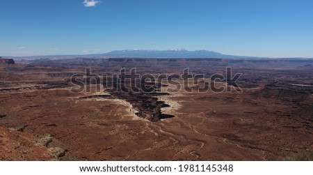 Post card style picture of canyonlands national park near Moab, UT, with deep gulleys and canyons and rocky mountains in the background