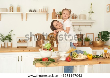 Healthy food at home. A cheerful mother laughs, has fun and hugs her daughter