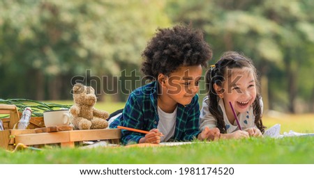 diverse mixed race kids boy and girl as friends having fun playing together during picnic in park in summer Royalty-Free Stock Photo #1981174520