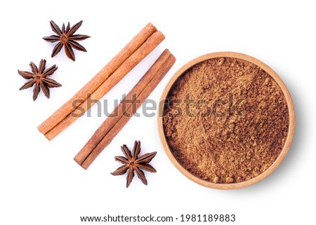 Cinnamon powder in wooden bowl with cinnamon sticks and star anise isolated on white background. Top view, Flat lay. Royalty-Free Stock Photo #1981189883