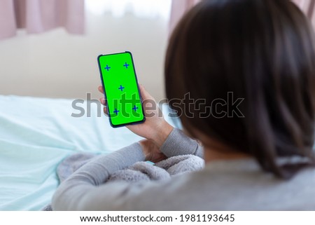 asian female use green screen mobile phone on the bed